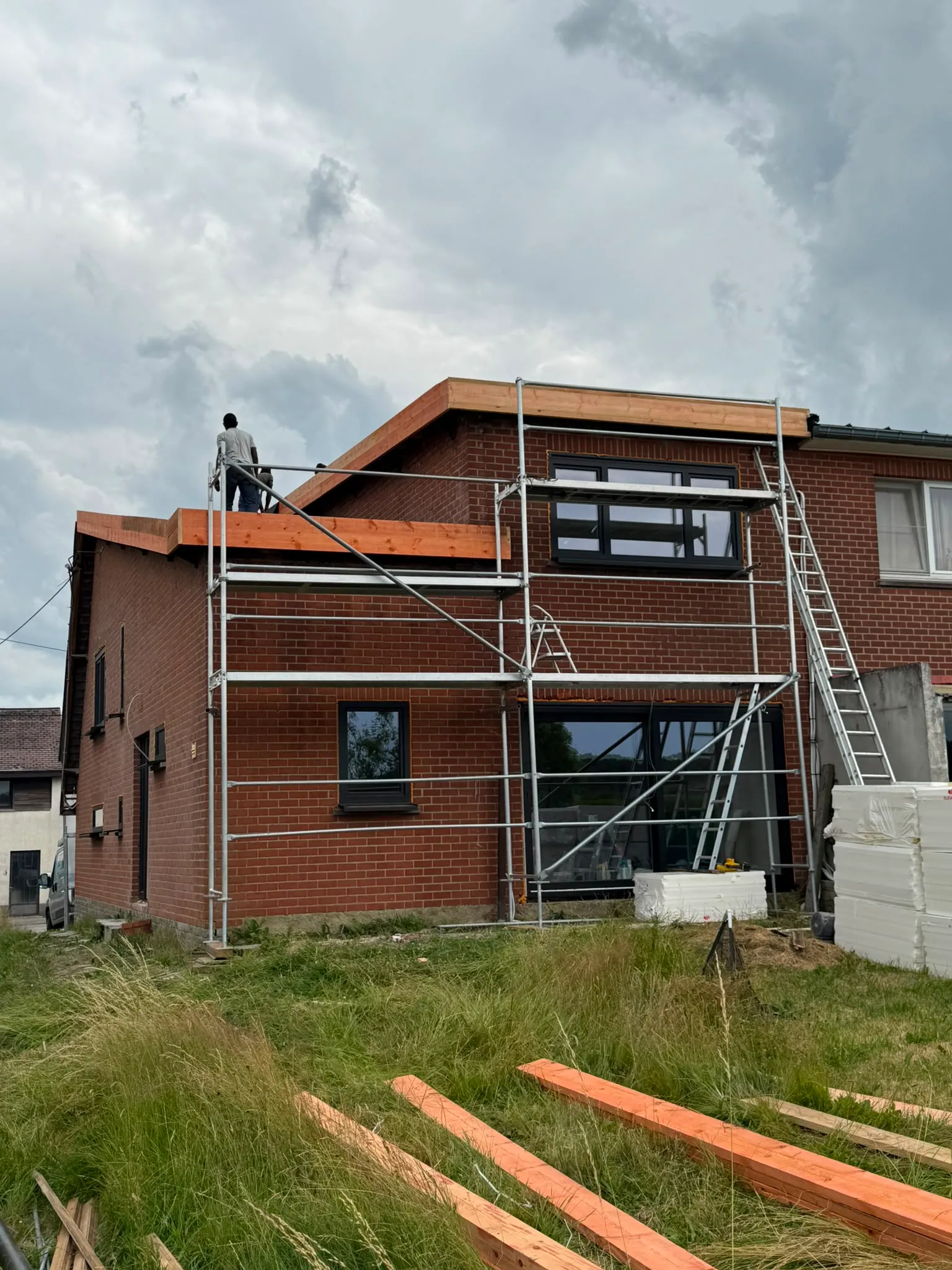 Couvreur posant une planche de rive en bois sur un échafaudage