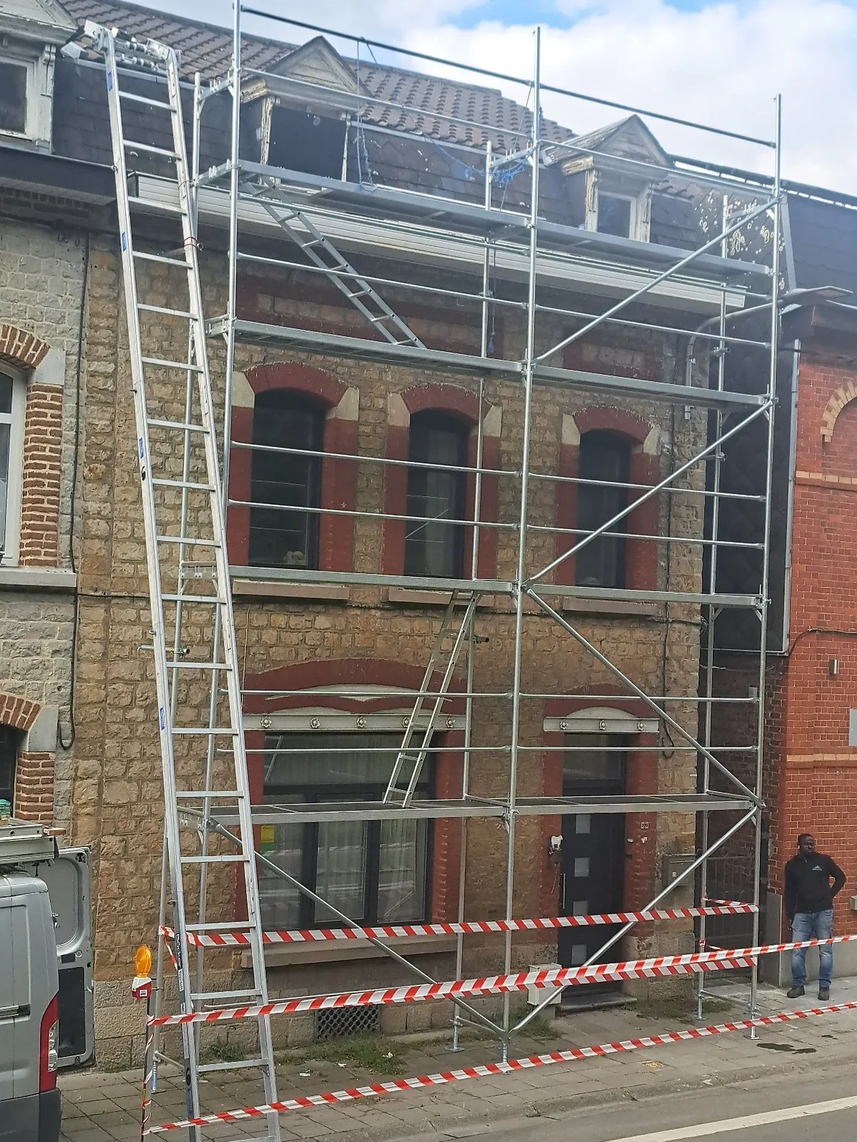 Échafaudage monté devant une façade en pierre pour la rénovation d’une toiture, Dinant