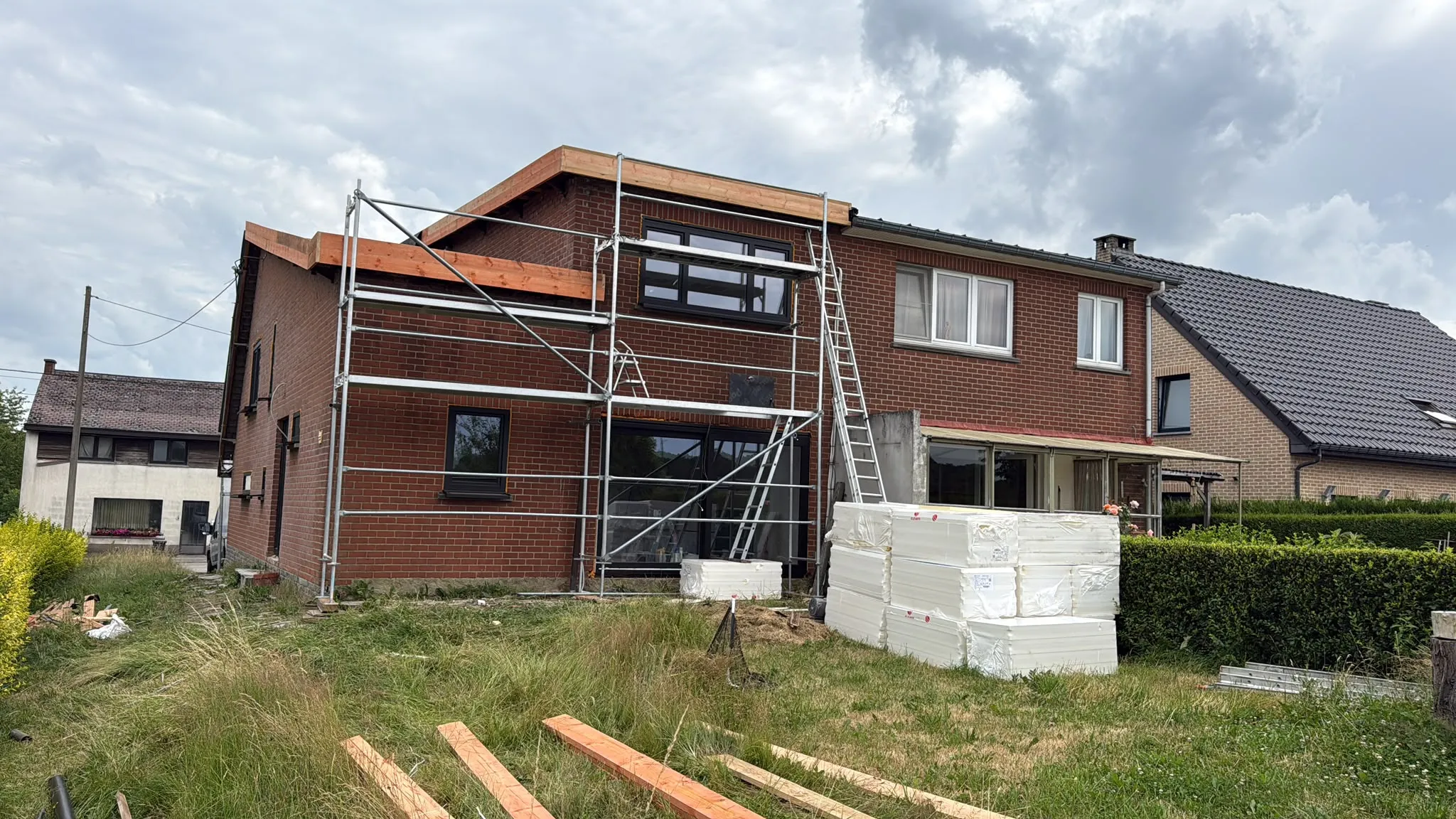 Chantier de rénovation sous échafaudage, bois de charpente neuf apparent en débord de toit