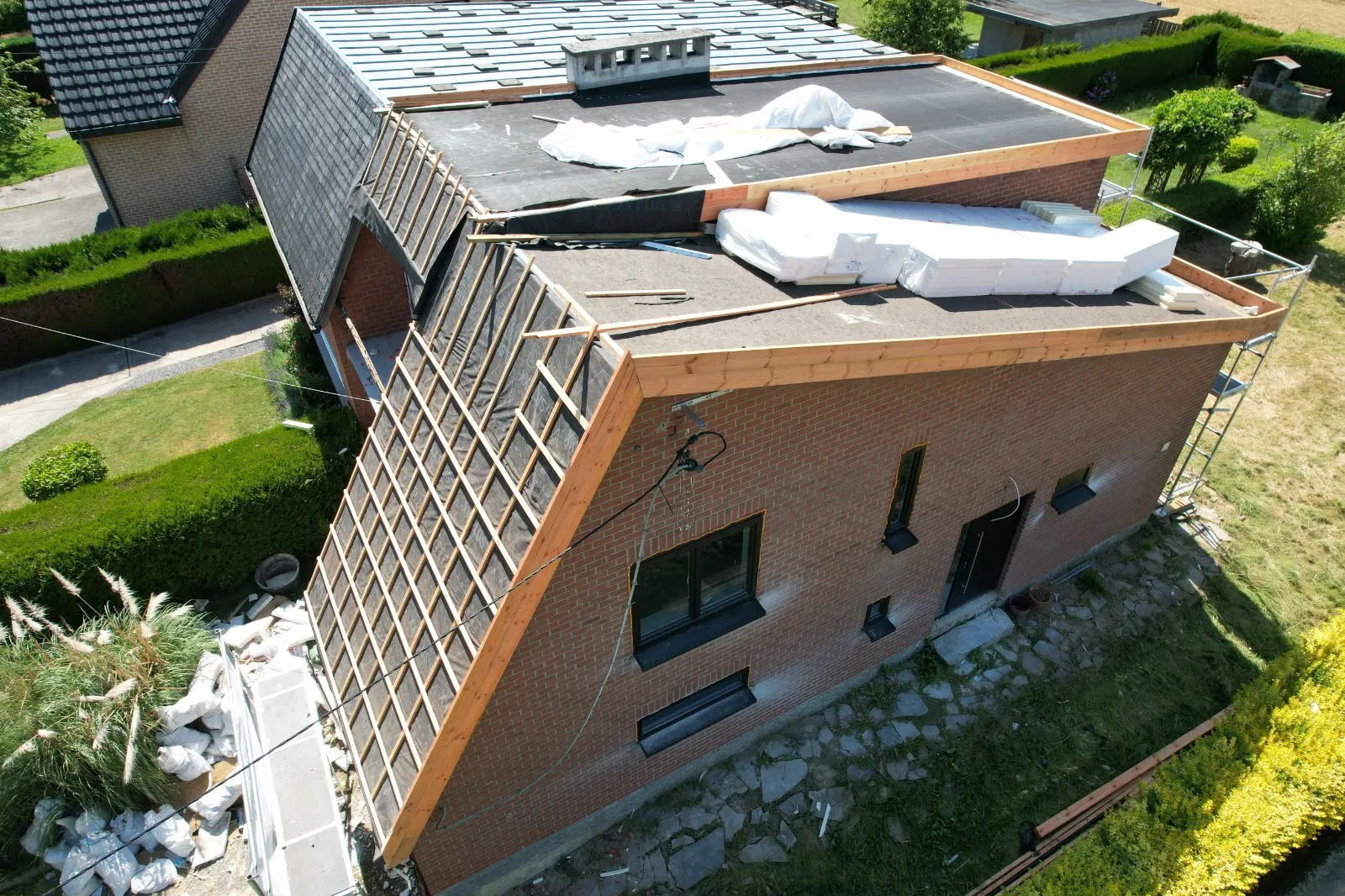 Vue aérienne d’un versant en cours de lattage à côté d’une toiture plate isolée, Namur