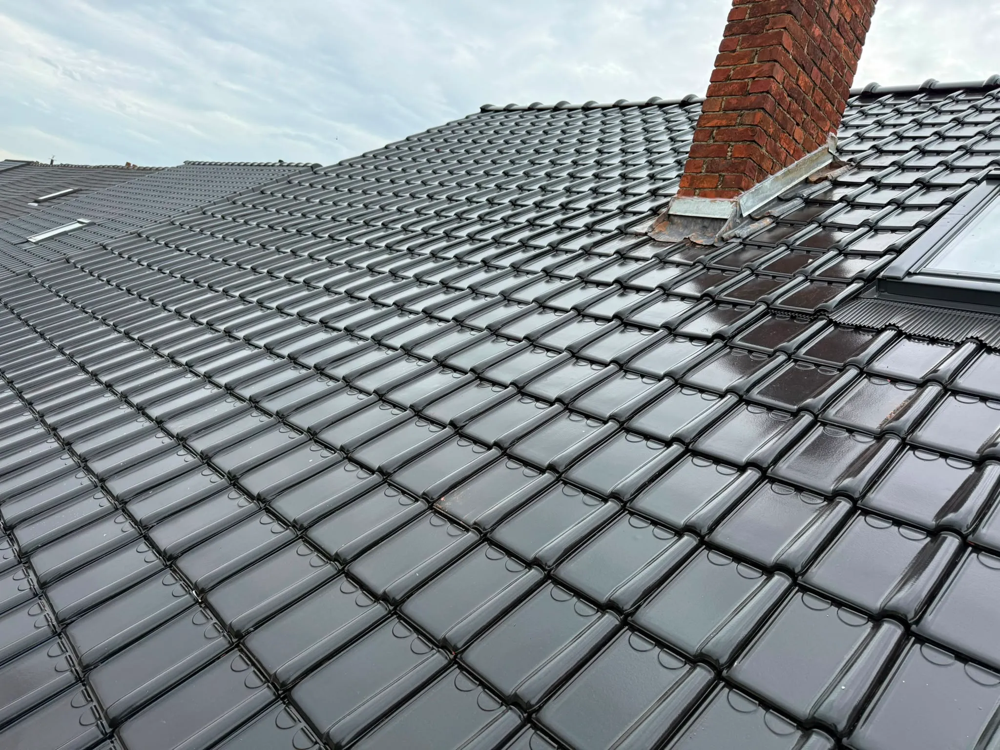 Grande cheminée en briques avec solin métallique sur une toiture en tuiles noires, Namur