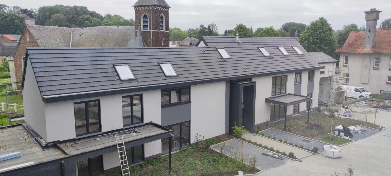 Vue aérienne d’un grand bâtiment rénové avec toiture neuve en tuiles anthracite et fenêtres de toit, Eghezée