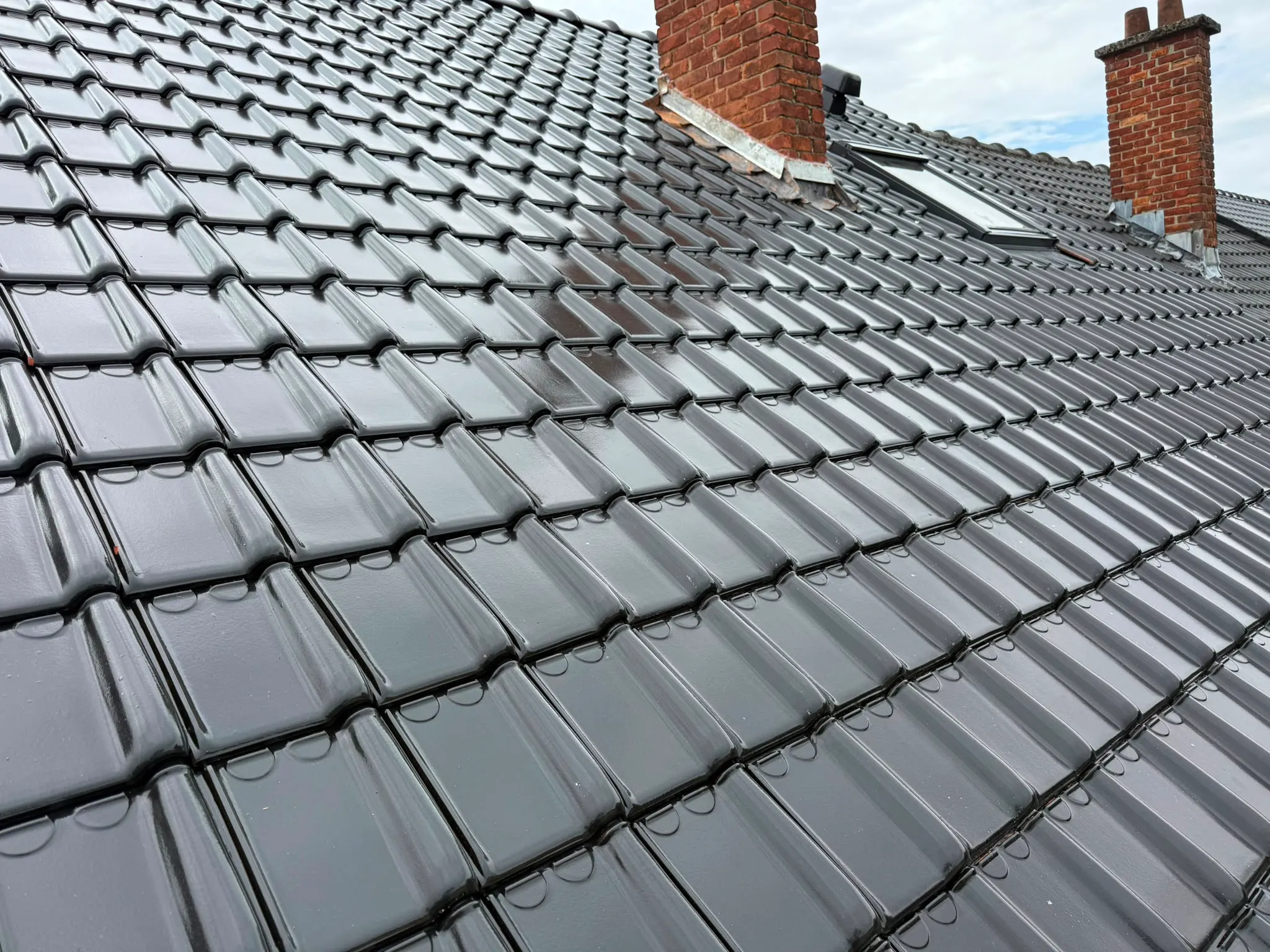 Pan de toiture en tuiles noires avec deux souches de cheminée et une fenêtre de toit, Namur