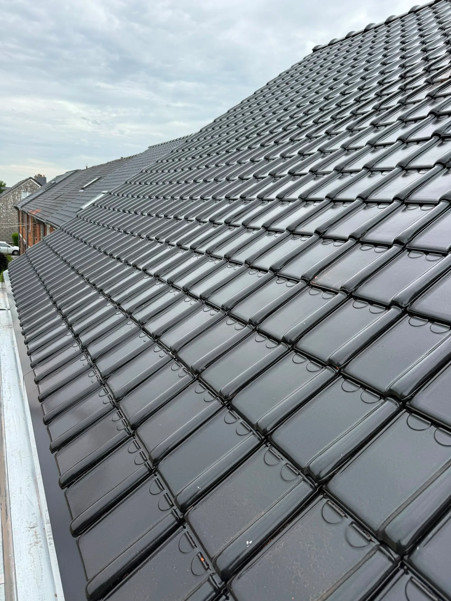 Long pan de toiture en tuiles noires avec gouttière en zinc, Namur