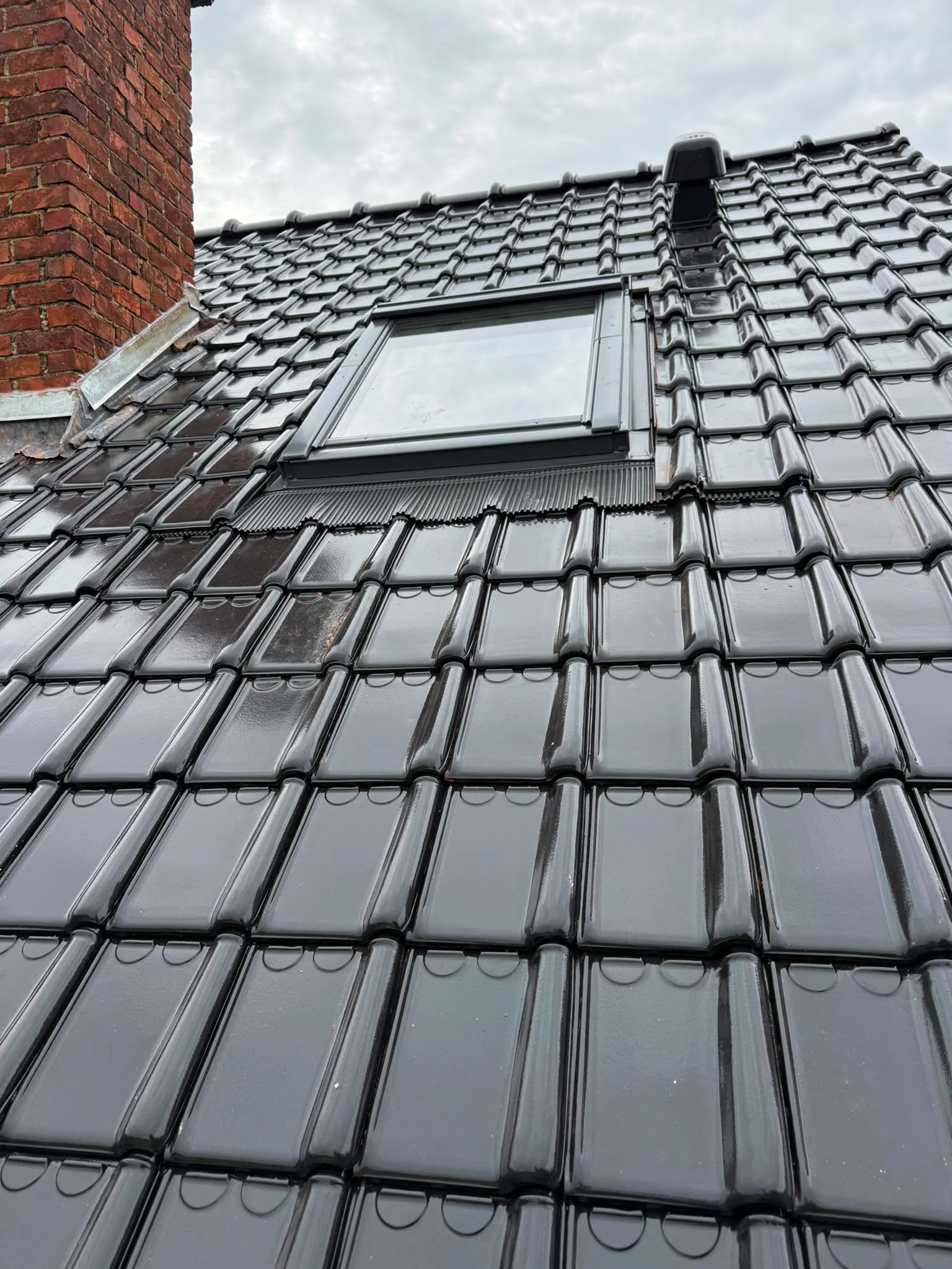 Toiture en tuiles noires avec fenêtre de toit, cheminée et sortie de ventilation, Namur