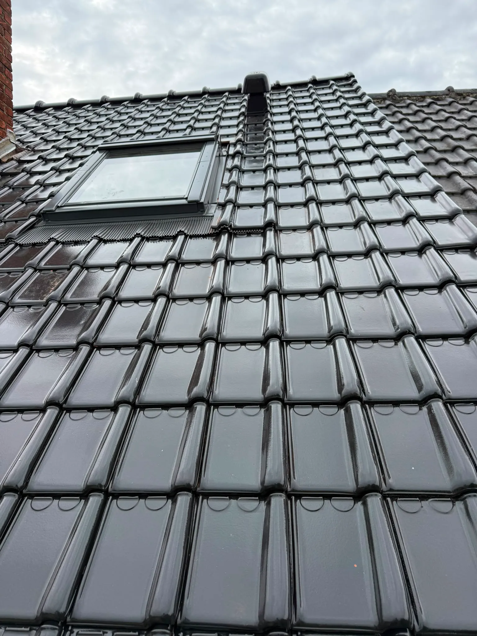 Toiture en tuiles noires neuves avec fenêtre de toit encastré et sortie de ventilation, Namur