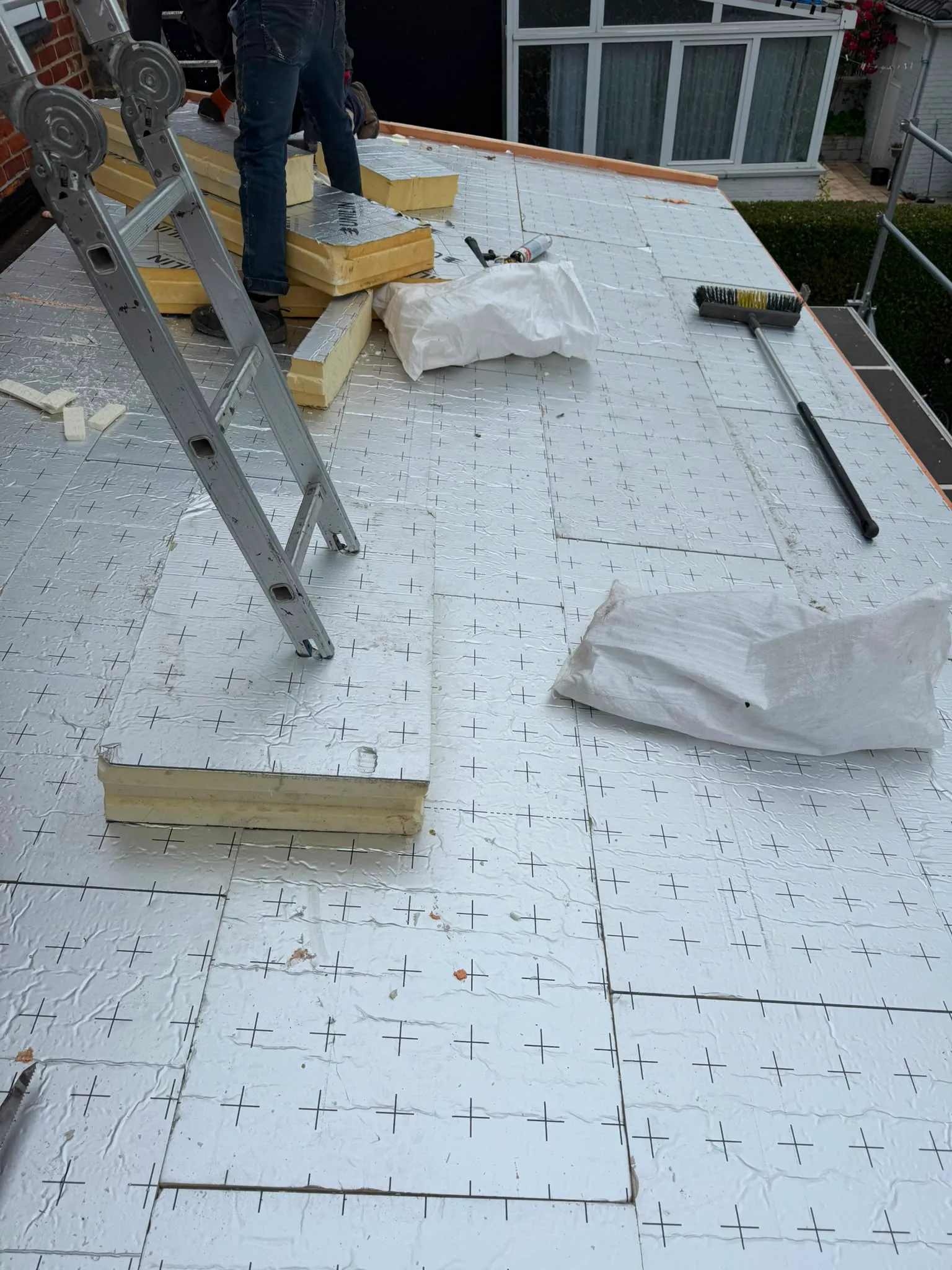 Toit plat en cours d’isolation avec panneaux à parement aluminium et couvreur à l’échelle, Namur