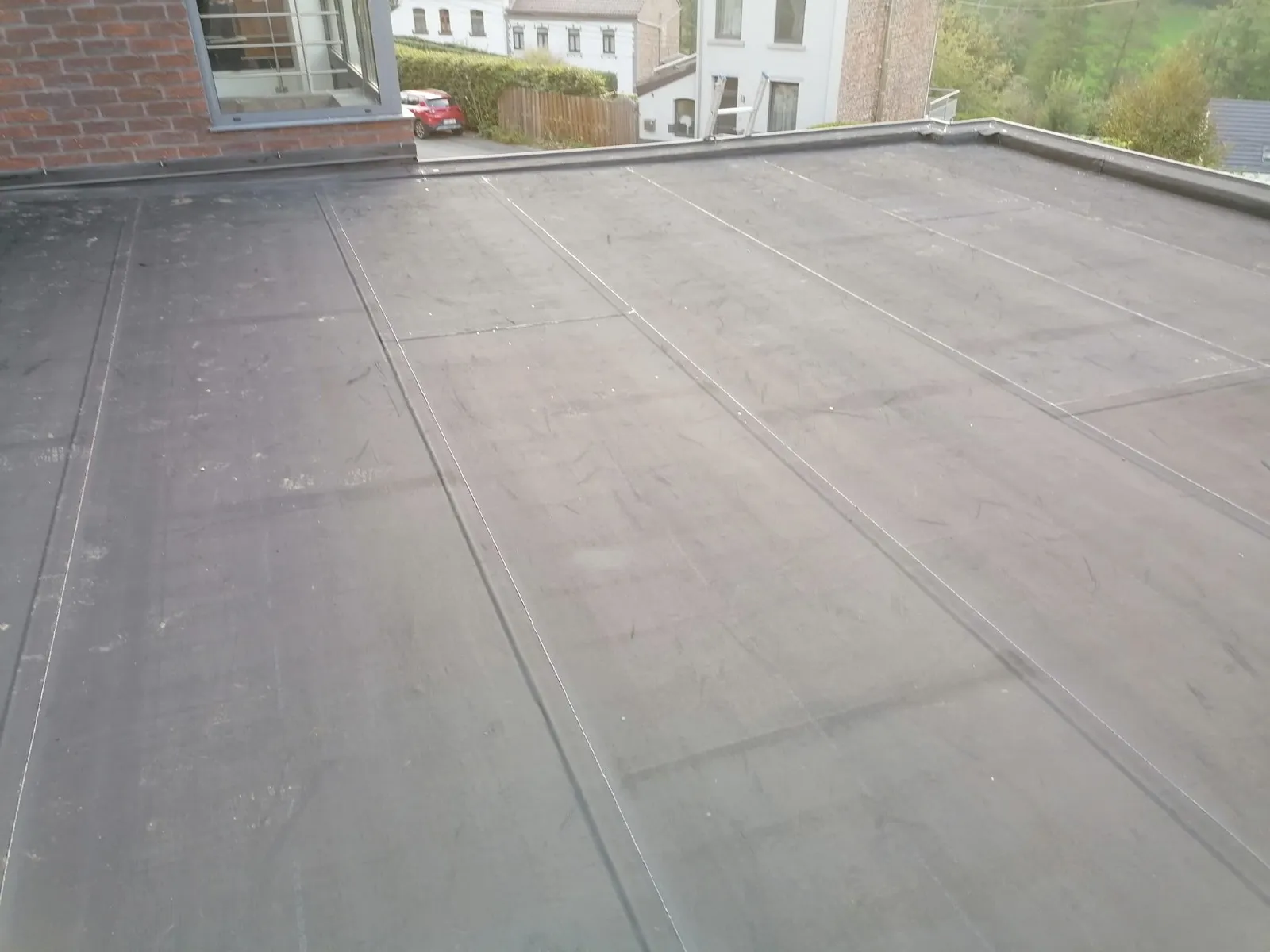 Toiture plate neuve en membrane bitumineuse noire sur maison en pierre, vue sur la vallée