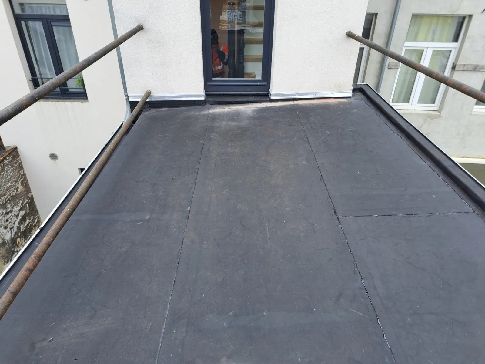 Toiture plate en membrane noire terminée devant une porte-fenêtre, Namur
