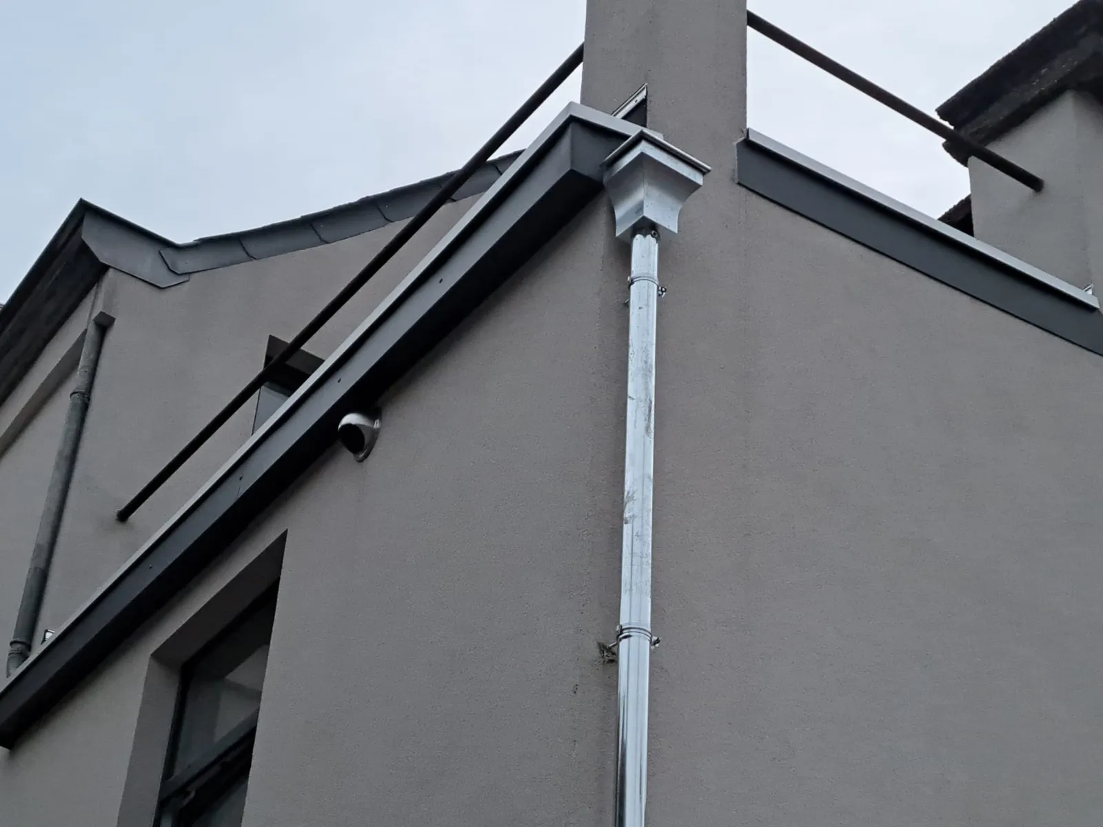 Détail d’un angle de gouttière et de descente en zinc au raccord de deux pans de toiture, Namur