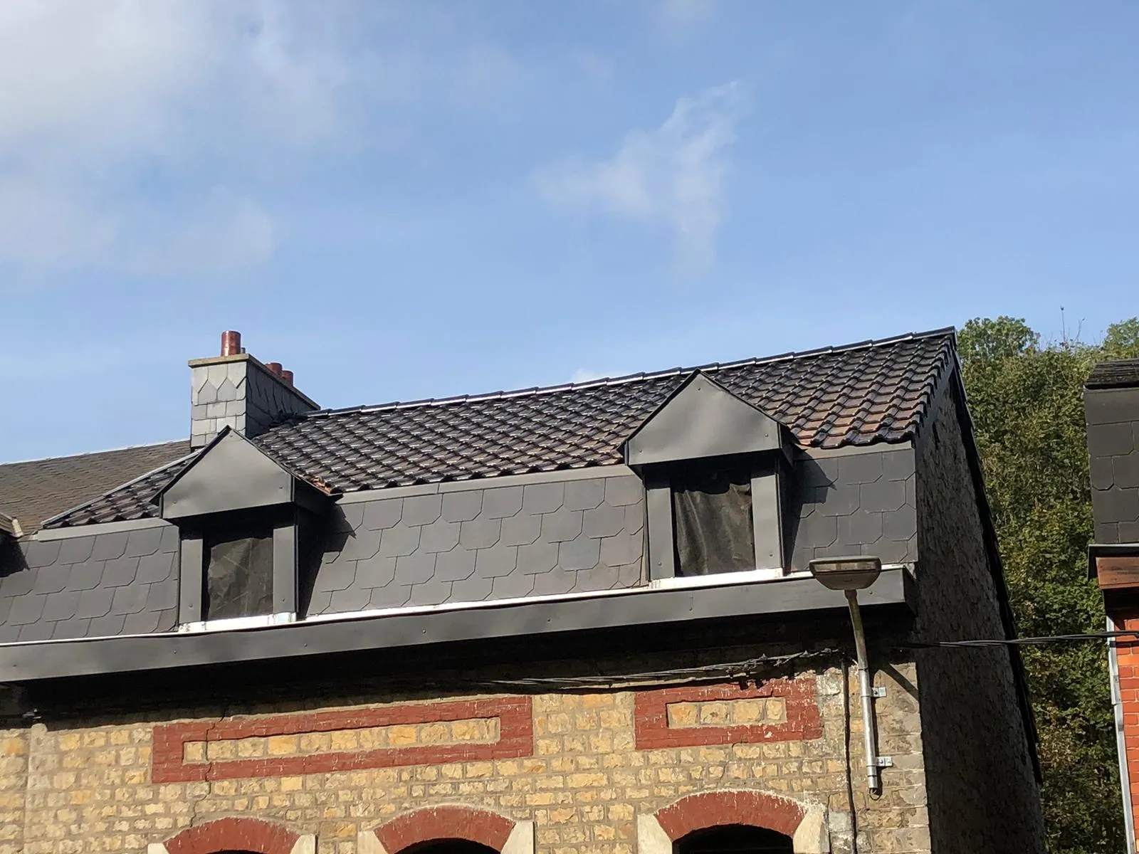 Lucarnes habillées d’ardoises et de zinc sur un bâtiment en pierre