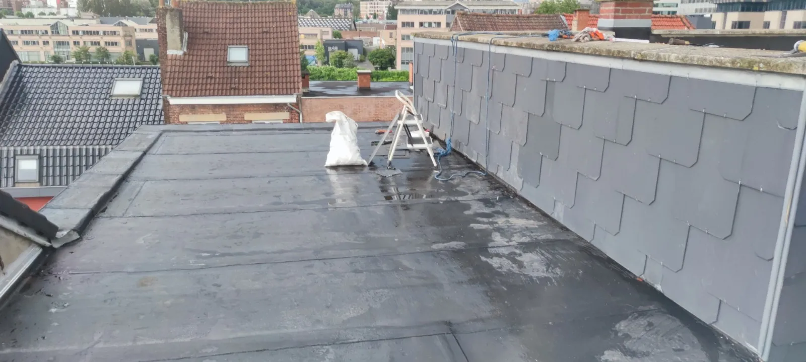 Mur d’acrotère habillé d’ardoises losangées au-dessus d’une toiture plate